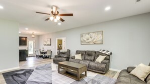 A spacious living room with a gray sectional sofa, a coffee table, and a large abstract rug. - 11 Mi to Troy University: Family Home w/ Yard (Troy)