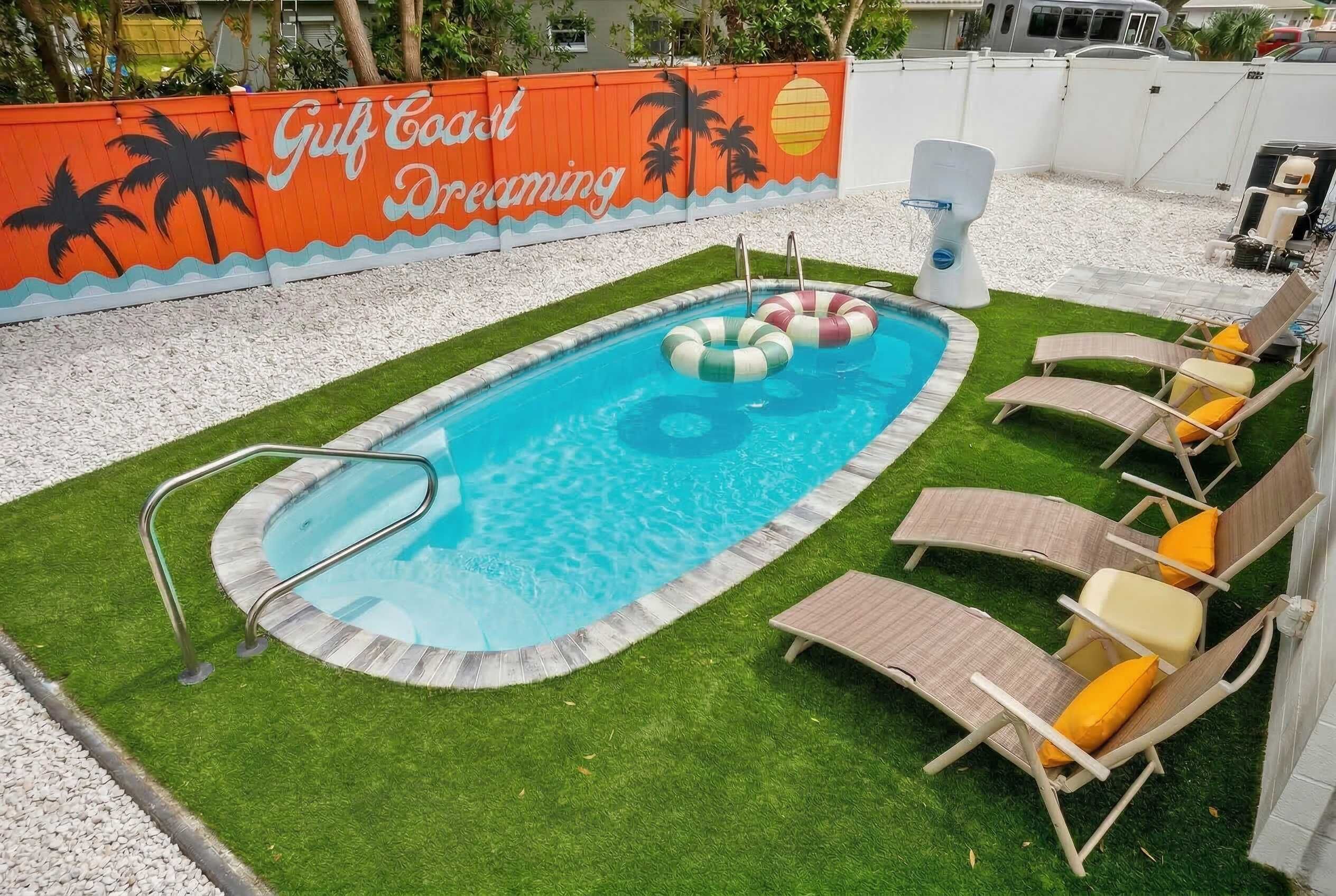 Piscina con un murale di palme, sedie a sdraio e una piccola fontana.