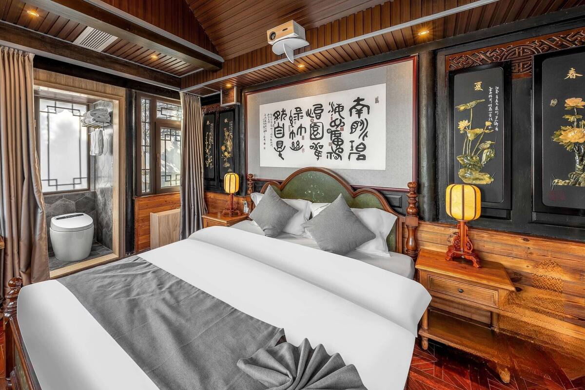 A traditional-style bedroom with a large bed, wooden headboard, and a wall-mounted artwork.
