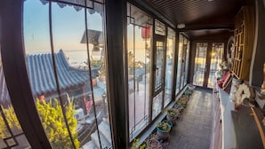 A corridor with large windows, potted plants, and traditional architectural elements. - Laoshan Swan Castle Vacation Garden B&B (Qingdao)