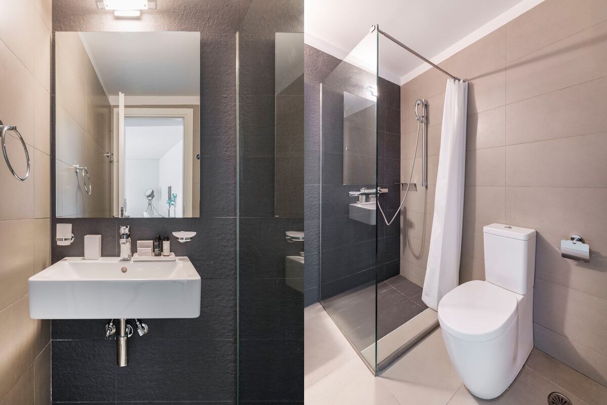 A modern bathroom with a glass-enclosed shower, a white sink, and a toilet.
