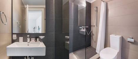 A modern bathroom with a glass-enclosed shower, a white sink, and a toilet.