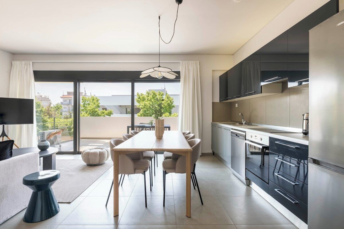 A modern kitchen with a dining area, large windows, and a view of the city.