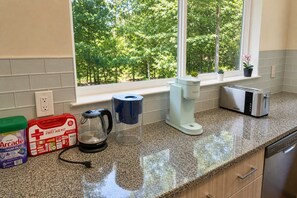 A kitchen with a window, a coffee maker, a toaster, and a first aid kit on the counter. - Cozy Huguenot Hideaway (Huguenot)