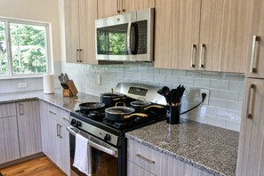 A modern kitchen with a stainless steel stove, a microwave above it, and wooden cabinets.