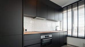 A modern kitchen with dark cabinetry, a wooden countertop, a built-in oven, and a window with blinds. - Mallorca with sunny balcony by Interhome (Blankenberge)
