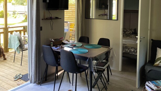 Un espace repas comprenant une table, des chaises et un téléviseur fixé au mur.