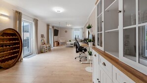 A modern kitchen with a wooden wine rack, a dining area with a table and chairs, and a large window with curtains. - Stay in the Heart of Nature (Sankt Wendel)
