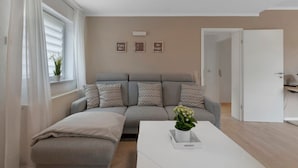 A modern living room with a grey sofa, a white coffee table, and a potted plant. - Stay in the Heart of Nature (Sankt Wendel)