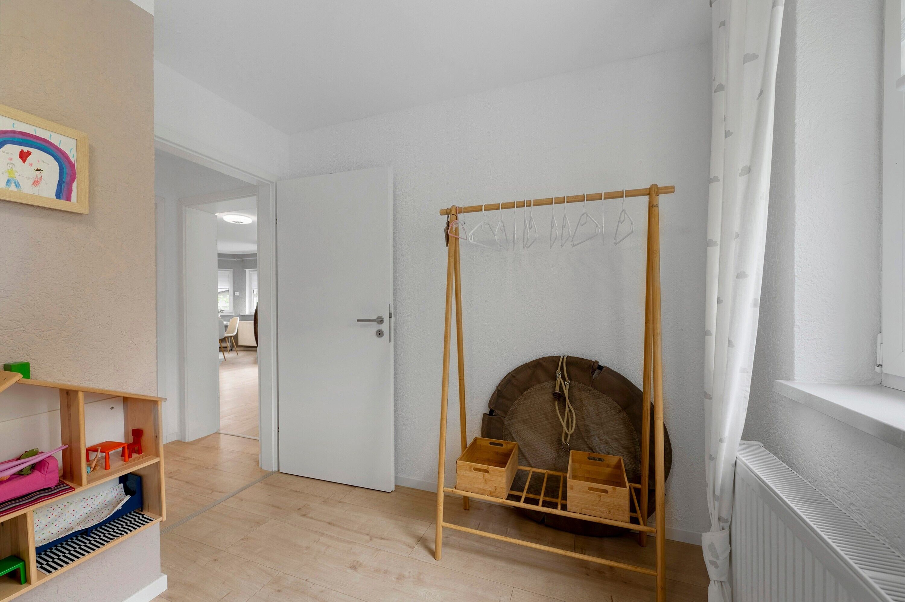 Ein Zimmer mit Holzregal, einer Tür, einer Kleiderstange und einer Heizung.