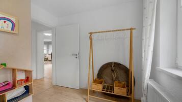 Ein Zimmer mit Holzregal, einer Tür, einer Kleiderstange und einer Heizung.