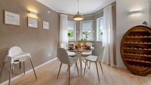 A dining area with a round table, chairs, a wine rack, and wall-mounted light fixtures. - Stay in the Heart of Nature (Sankt Wendel)