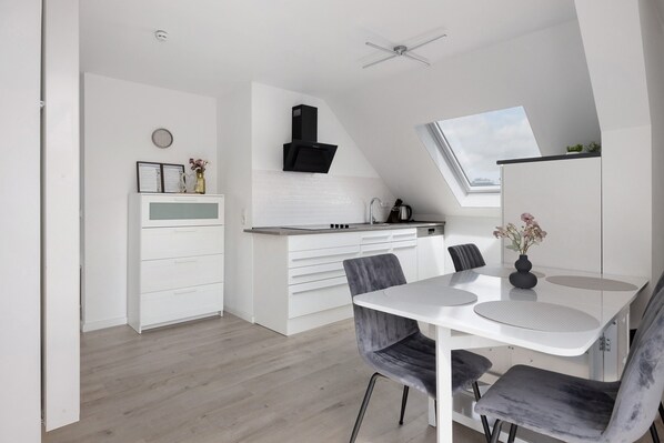A modern kitchen with white cabinetry, a black range hood, and a skylight.