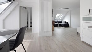 Un appartement moderne de style « loft » comprenant un coin repas, un espace de vie avec un canapé et une table basse, ainsi qu’une cuisine.
