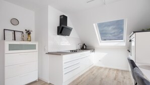 Une cuisine moderne avec des meubles blancs, une cuisinière encastrée et un puits de lumière.