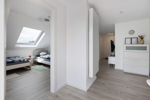 A bedroom with a skylight, a bed, a bedside table, and a dresser.