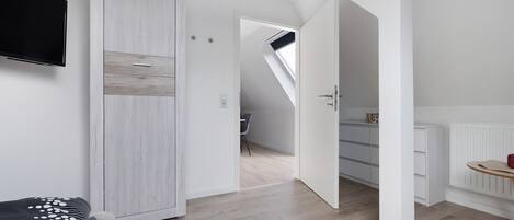 Un dormitorio con cama, armario, televisor y vistas a una escalera.