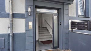 Une entrée d’immeuble avec une porte, un escalier et une boîte aux lettres.