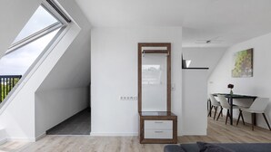 A modern room with a skylight, a wooden cabinet, a dining area with a table and chairs, and a gray sofa. - Apartment '2' with Wi-Fi (Bad Salzuflen)