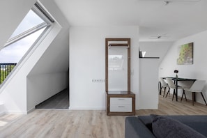 A modern room with a skylight, a wooden cabinet, a dining area with a table and chairs, and a gray sofa.