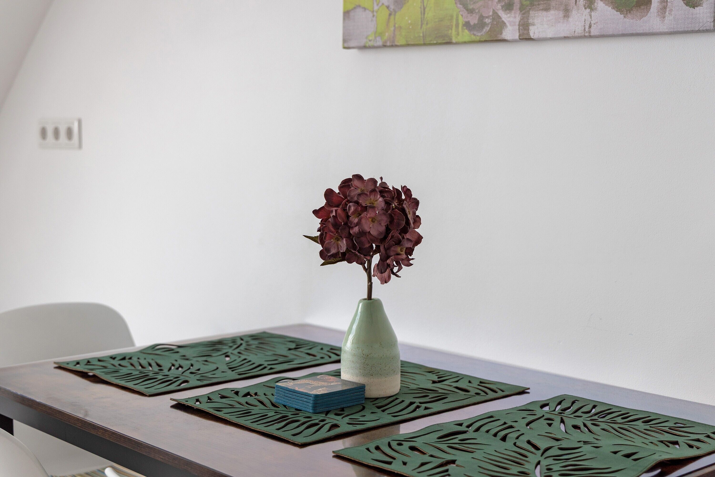 Ein Tisch mit einer Blumenvase, einem Kartenstapel und dekorativen Ausschnitten.