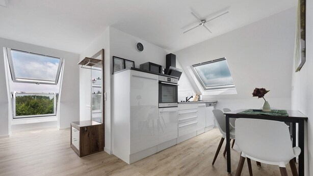 A modern kitchen with white cabinetry, a built-in oven, and a dining area with a table and chairs. - Apartment '2' with Wi-Fi (Bad Salzuflen)