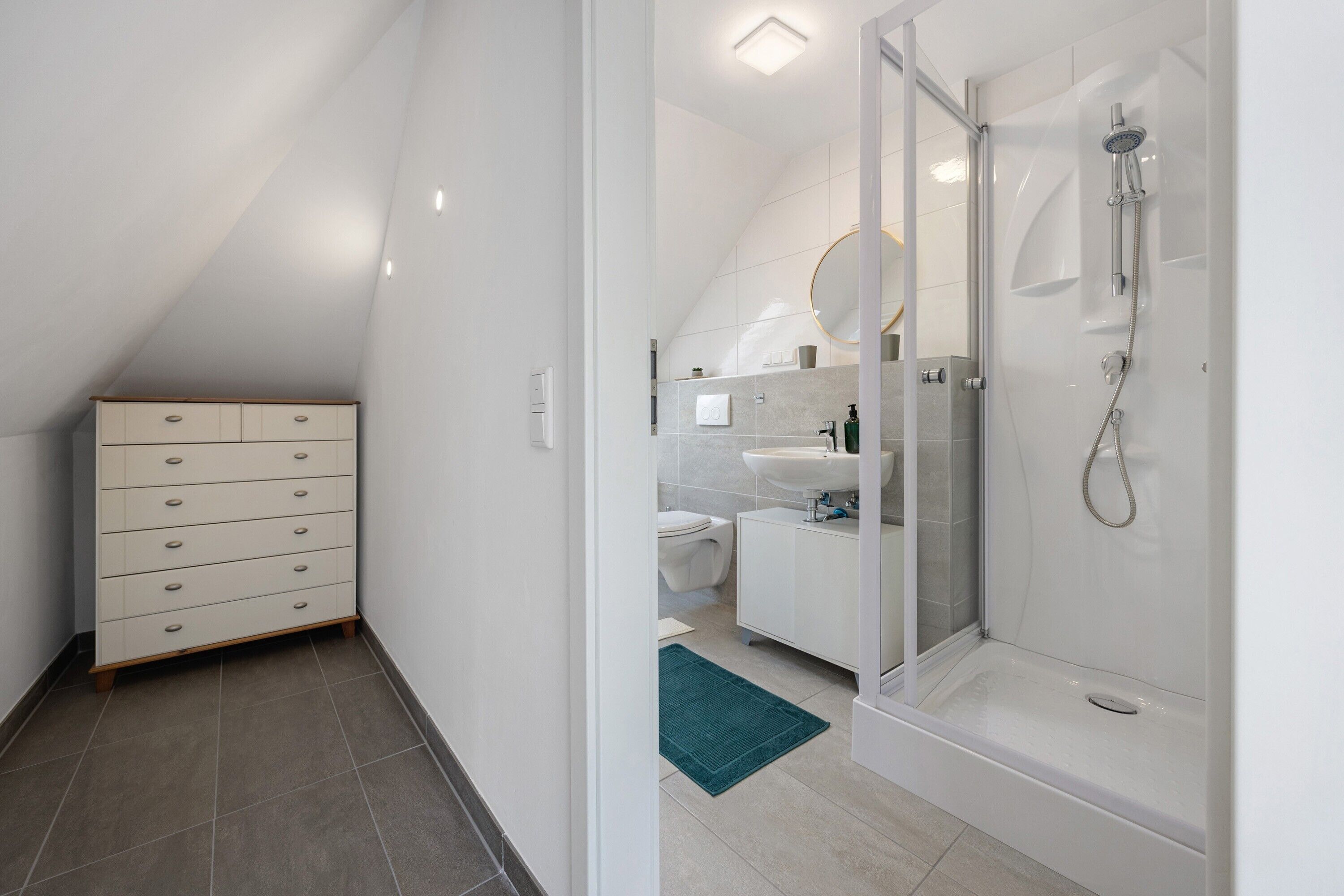A modern bathroom with a shower, toilet, and a dresser.