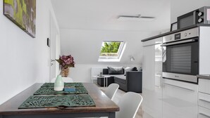 A modern kitchen with a built-in oven, a dining area with a table and chairs, a small sofa, and a skylight. - Apartment '2' with Wi-Fi (Bad Salzuflen)