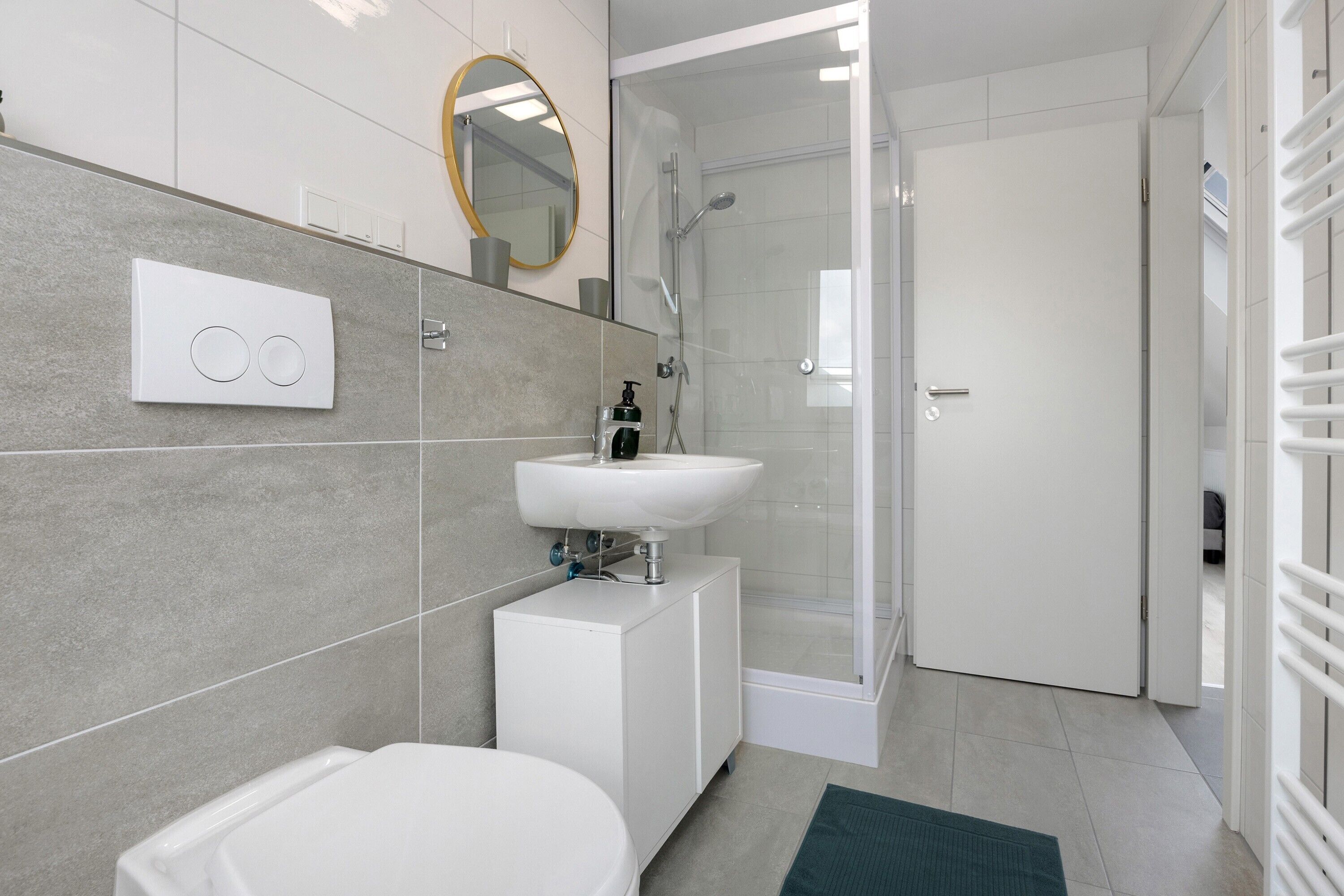 A modern bathroom with a toilet, sink, shower, and a glass-enclosed shower area.