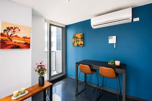 A modern room with a blue accent wall, a dining area with two chairs, a table, and artwork. - Cozy Melbourne City Retreat (Melbourne)