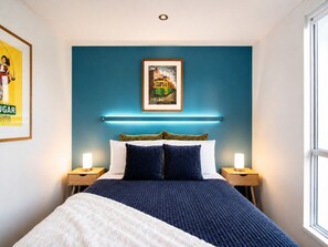 A bedroom with a bed, two bedside tables, a framed picture on the wall, and a window. - Cozy Melbourne City Retreat (Melbourne)