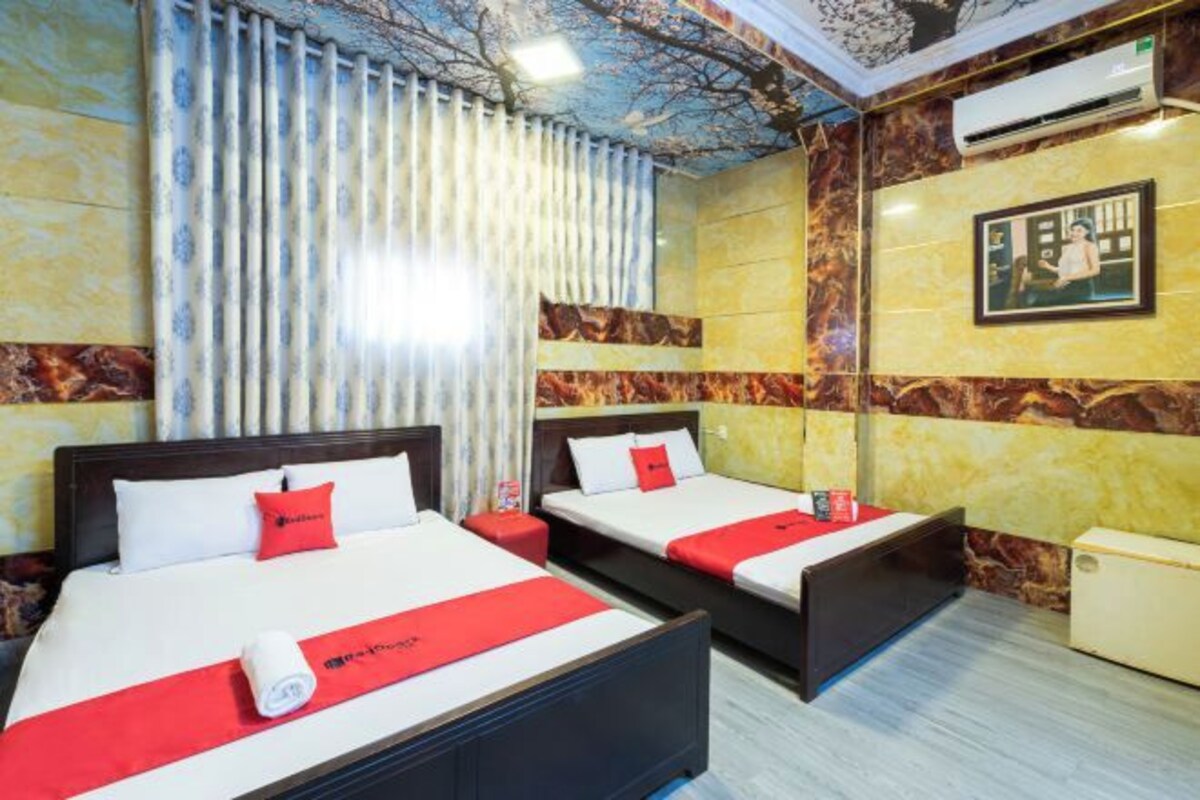 Une chambre d’hôtel avec deux lits, une fresque au plafond, un appareil de climatisation et un tableau encadré au mur.