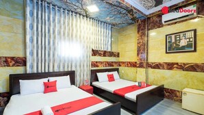 Habitació d'hotel amb dos llits, un estovat vermell i blanc, un coixí vermell, i un quadre encapçalat a la paret.