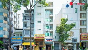Un edifici d'àmbitió amb diversos comerços a la planta baixa, com ara una clínica dental i un restaurant.