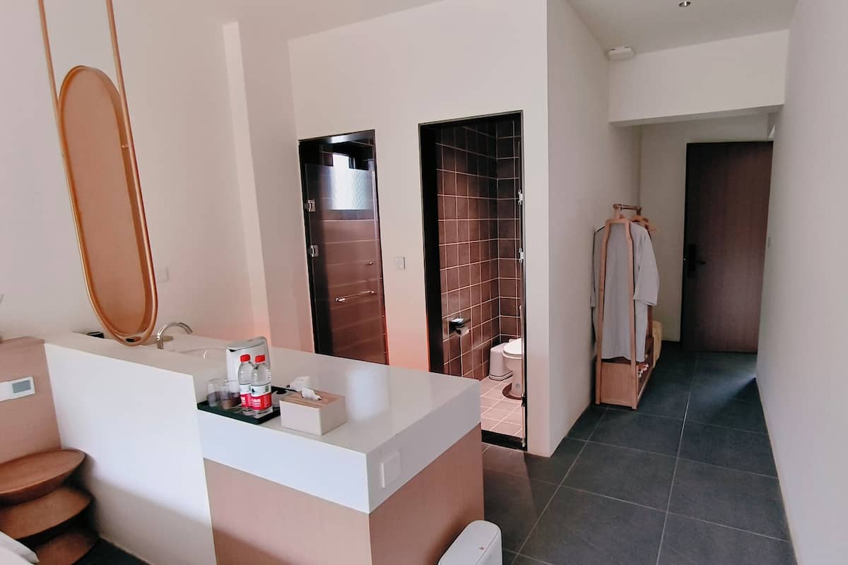 Un baño moderno con un espejo grande, un lavamanos y un inodoro. Se ve un perchero con una toalla.