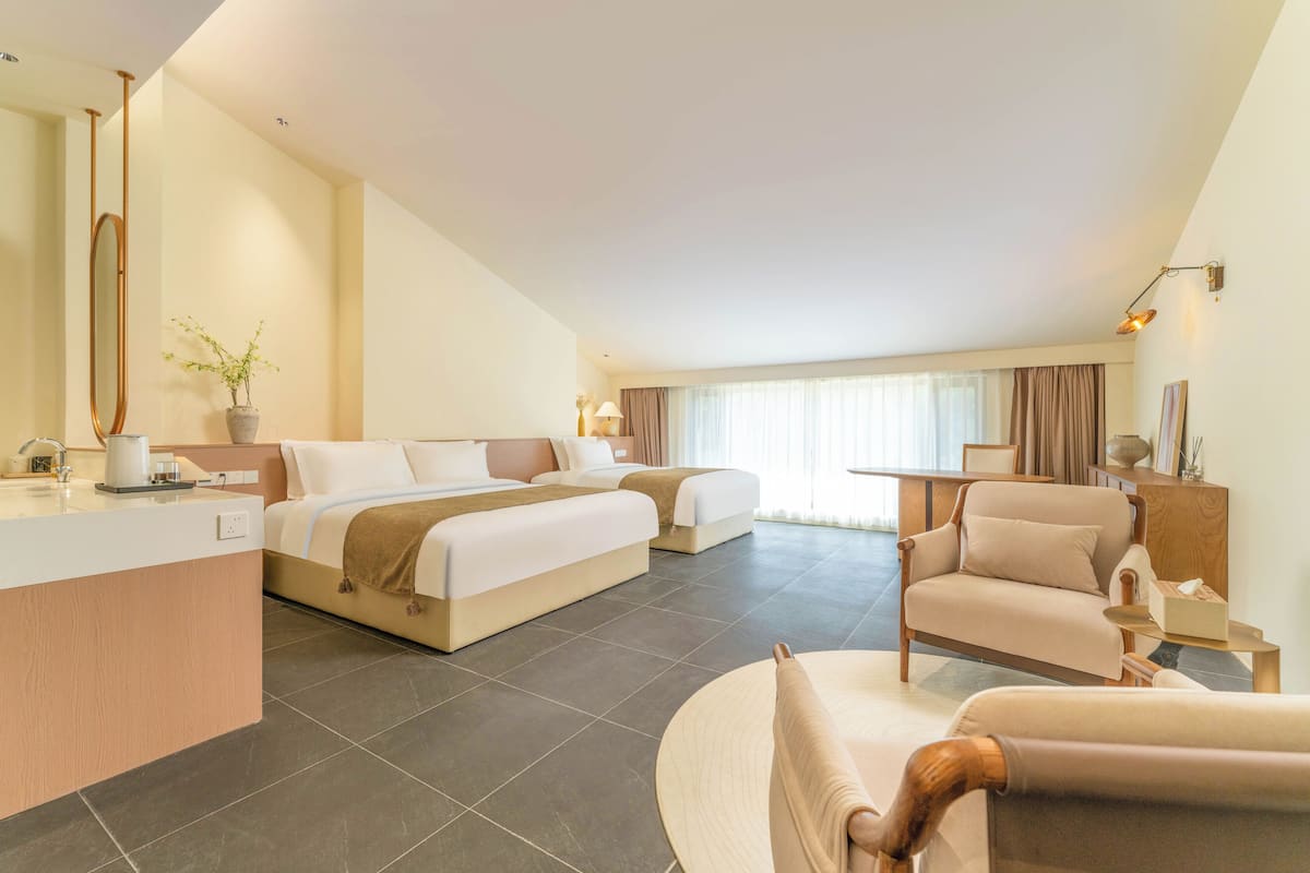 Una habitación de hotel moderna con una cama grande, un sofá, una silla, una mesita y un escritorio con un espejo.