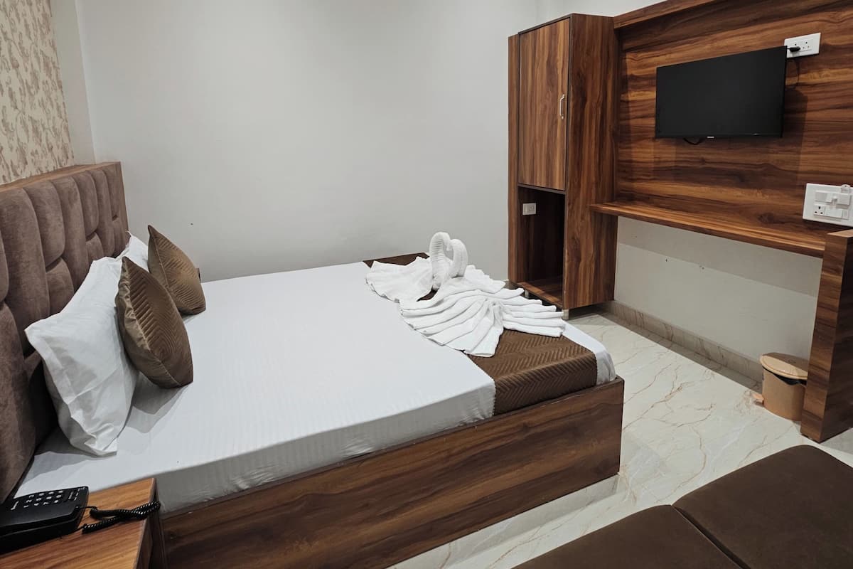 Un dormitorio moderno con cama, cabecero de madera, televisor montado en la pared y ventilador de techo.