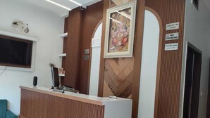 A reception area with a wooden reception desk, a computer, and a framed artwork on the wall. - Hotel RS INN (Amritsar)