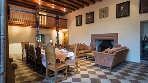 A dining area with a checkered floor, wooden furniture, and a fireplace. - Historic 6-Bedrooms Castle Retreat (Cupar)