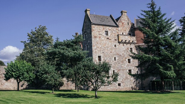 A historic stone building with multiple towers and a well-maintained lawn. - Historic 6-Bedrooms Castle Retreat (Cupar)