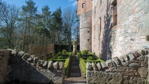 A stone building with a tower, a stone pathway, and a hedge garden. - Historic 6-Bedrooms Castle Retreat (Cupar)