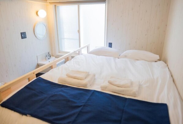 A hotel room with a bed, a bedside table, a mirror, and a window. - Niseko Powder Chalet (Kutchan)