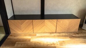 Ein Holzschrank mit Fischgrätmuster und schwarzen Metallbeinen.