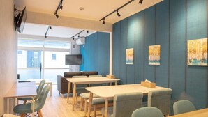 Ein moderner Konferenzraum mit Tischen, Stühlen, einer Couch und Kunstwerken an den Wänden.