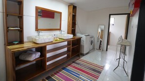 A modern bathroom with a wooden vanity, two sinks, a mirror, and a washing machine. - Natalei Eco Lodge  (Dawasamu)