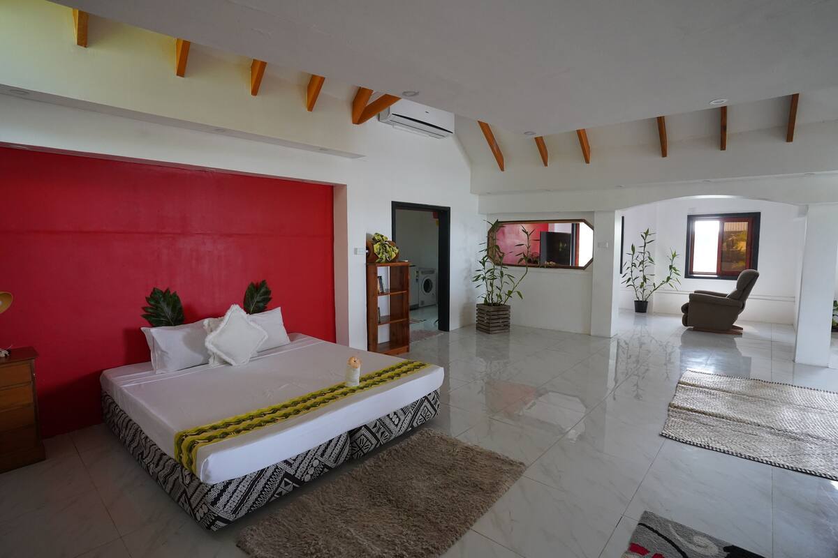 Un dormitorio amplio con una cama grande, una pared de acento roja y un diseño moderno.