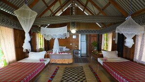 A traditional wooden room with two beds, each with a red plaid bedspread, a central bed with a floral arrangement, and a patterned rug. - Natalei Eco Lodge  (Dawasamu)