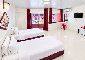 A hotel room with two beds, a desk, a chair, a TV, and a window with red curtains. - Arawana Express North Pattaya (Pattaya)