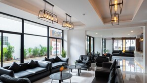 A modern lobby with leather sofas, round tables, and pendant lighting. Large windows offer views of the outside. - Arawana Express North Pattaya (Pattaya)