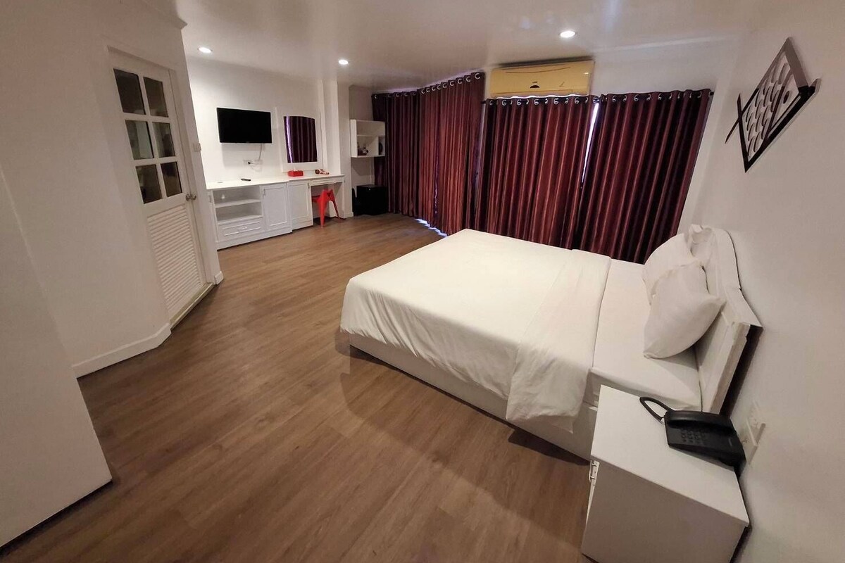 A hotel room with a bed, a desk, a TV, and a wardrobe.